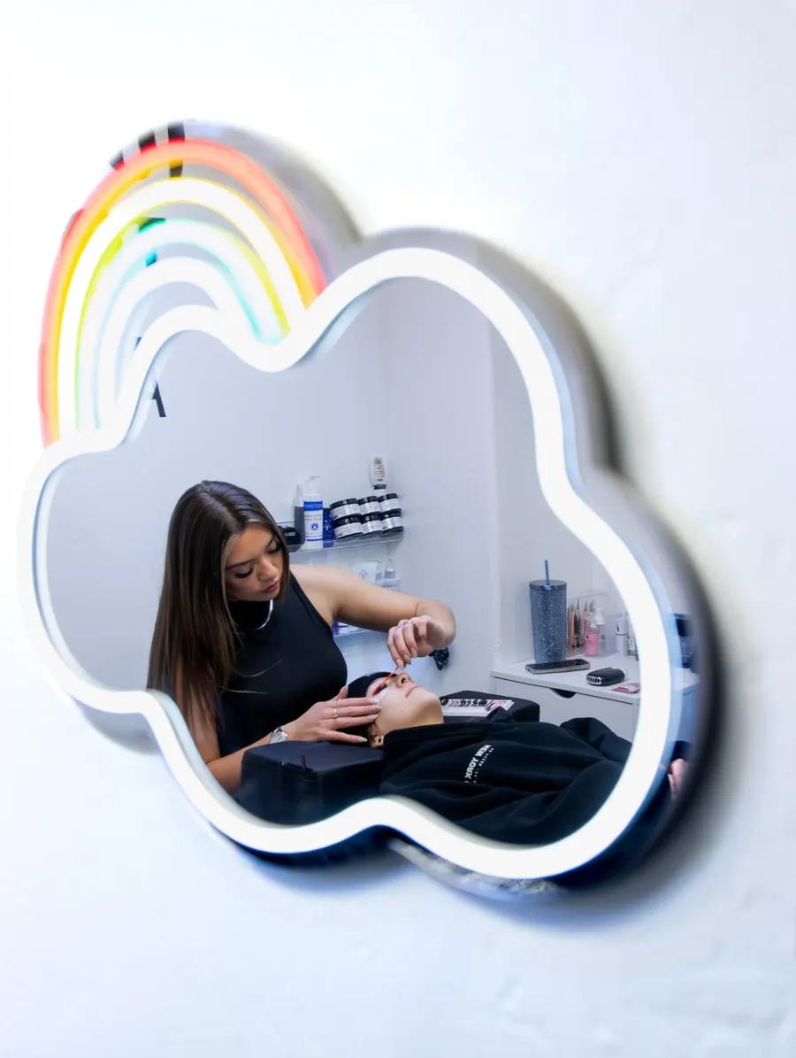 Rainbow cloud mirror in the GLAMSTHETICS SLC studio reflecting the esthetician at work